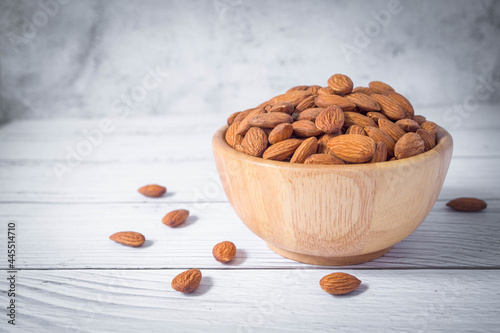 Tasty organic peeled almond snack in wooden bowl on white wooden background with copy space.Close up heap almonds shelled nut .Healthy food concept.