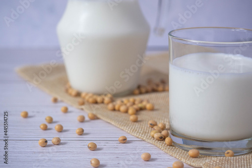Close up tasty organic homemade soy milk in glass and soybean or soya beans in glass bowl on a wooden table background.Soy milk is a beverage made from soy.Alternative milk and healthy concept.
