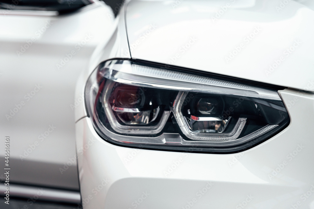 Front headlight of a white luxury modern suv car close up.