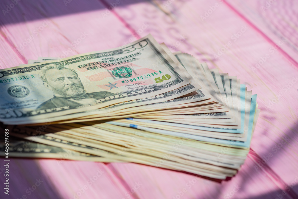 Closeup American cash banknotes. Dollars on a pink wooden background. Finance concept. Closeup American cash banknotes. Dollars on a pink wooden background. Finance concept.
