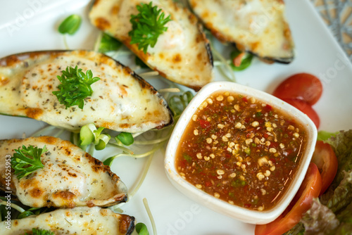A traditional Thai style spicy seafood dipping sauce in white bowl which is served with cheese baked mussel menu. Food object photo.