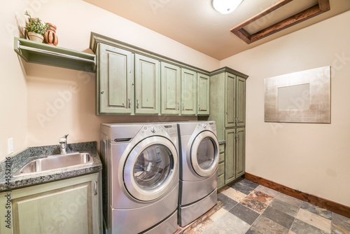 Laundry room interior with mint green cabinets and front load laundry appliances