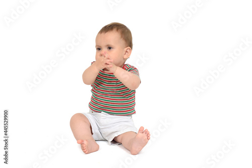 Ten month old baby sitting on the floor clapping on white background © curto