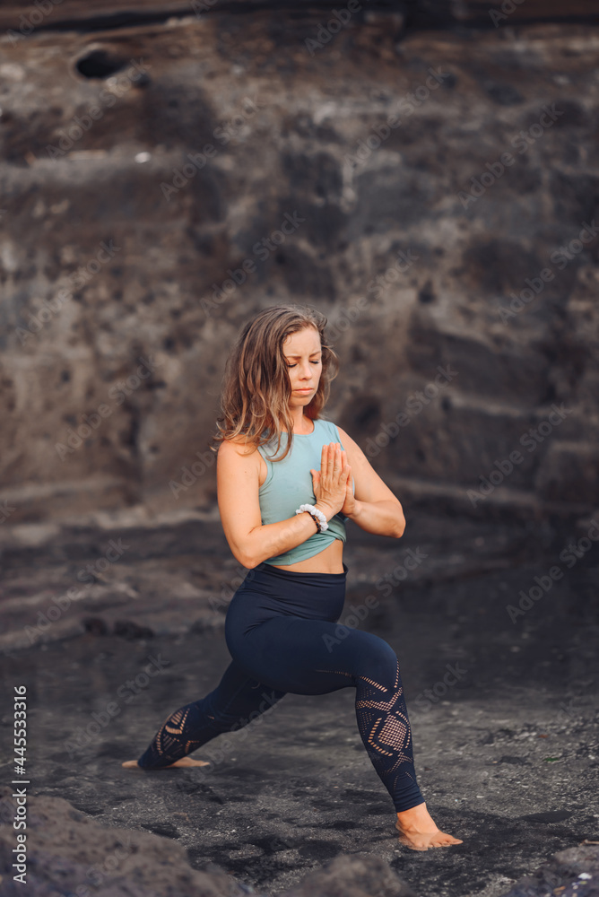 European girl doing yoga on the background of rocks..