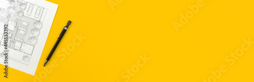 Banner construction and architect design concept. Residential building drawings and architectural blueprint on business desktop with pen. Yellow background and top view photo with copy space