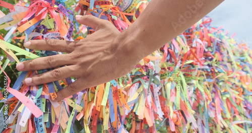 Closeup of colorful ribbons in Bahia, Brazil. Man hand making an request with Brazilian ribbons. Faith.