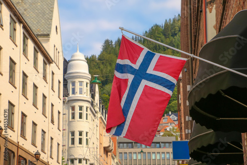 Typical street in Bergen, historic architecture, a Norweigan flag and  mountain of Fløyen in the background on a summer day. Norway.