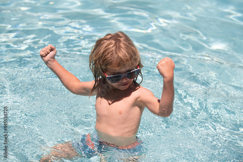 Child boy show muscles, swim in swimming pool. © Volodymyr