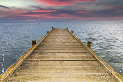 Wooden dock in the sea with a beautiful sunset in the background
