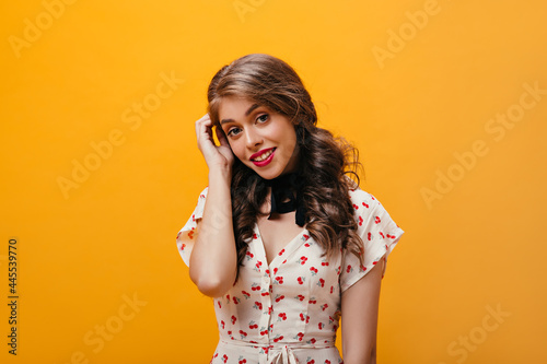 Portrait of charming woman in white dress. Lovely young girl with bright lipstick in cherry print clothes looking into camera..