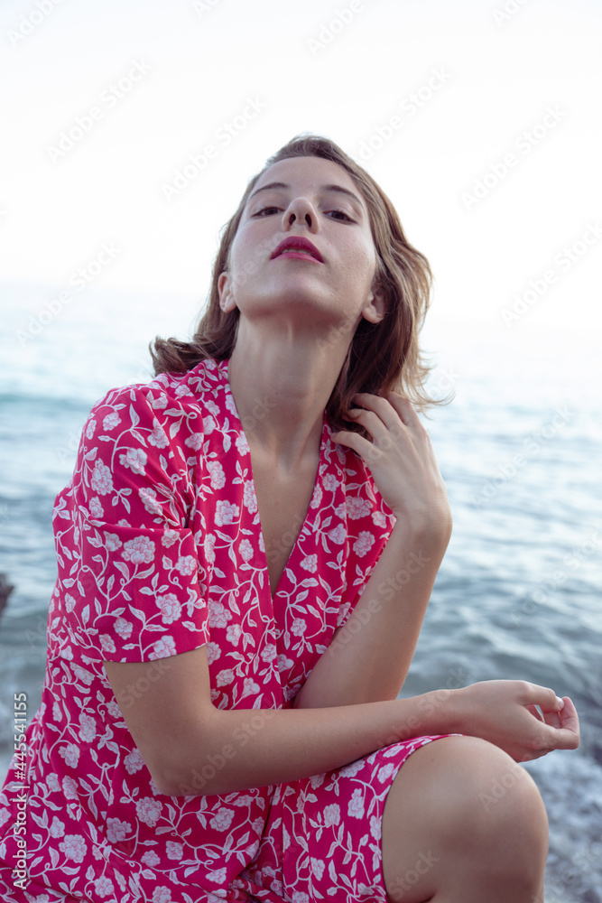 Natural beauty of as young woman enjoying her holidays in a beach of the coast side in a pink vintage flowers dress. Natural beauty of as young woman enjoying her holidays in a beach of the coast side in a pink vintage flowers dress.