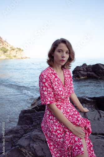 Natural beauty of as young woman enjoying her holidays in a beach of the coast side in a pink vintage flowers dress.