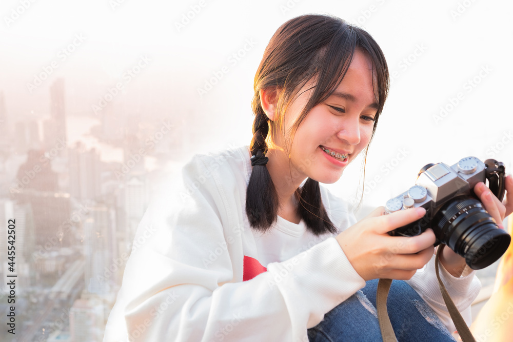 Beautiful teenager happy using camera at the city background Beautiful teenager happy using camera at the city background