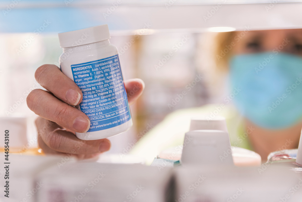 Close-up of female pharmacist hand holding bottle with pills in pharmacy