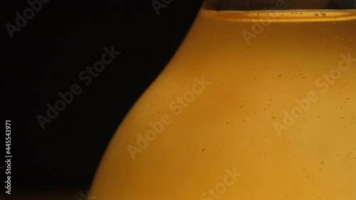 Fermenting honey in a glass bottle with carbonated bubbles fizzing and yeast taking some mildly visible shape within.