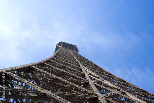 Close-up of Eiffel tower at high noon at springtime with cloudy blue sky background. Photo taken May 1st, 2019, Paris, France.