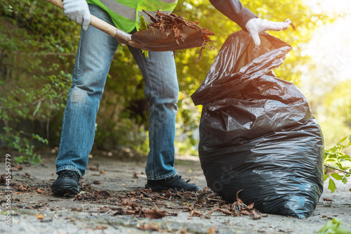 man volunteer clean up park or collect foliage with shovel in garbage bag