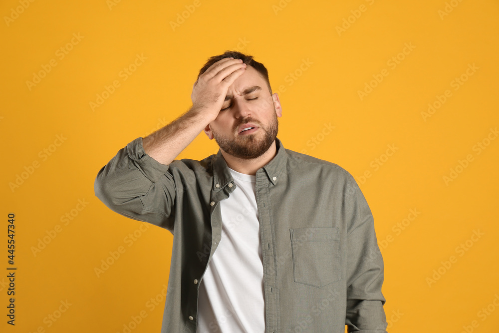 Man suffering from migraine on yellow background