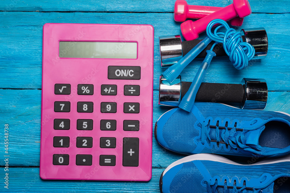 Gym cost calculation concept. Gym equipment and calculator on the table.