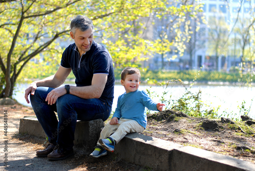 Fototapeta premium Father and son have a rest in the park near the river