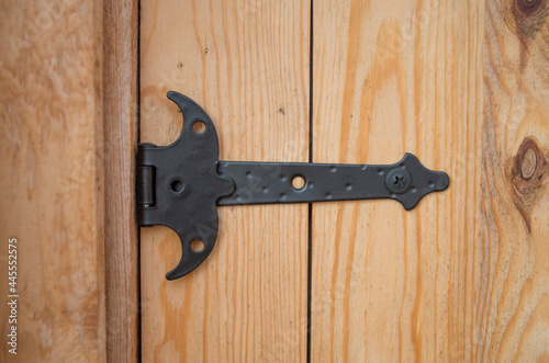 New black decorative metal hinge on wooden door