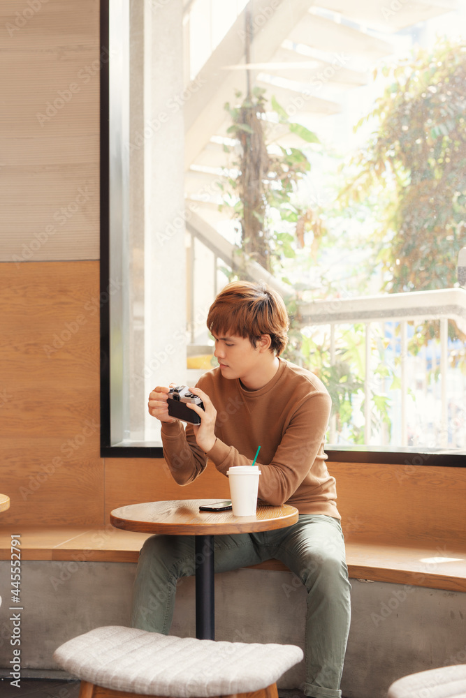 Asian man using camera sitting in a cafe.