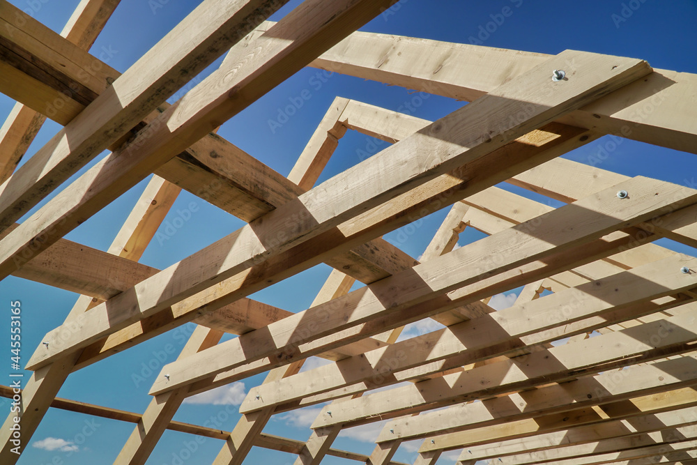 Obraz premium Roof construction. New residential construction home framing against a blue sky.