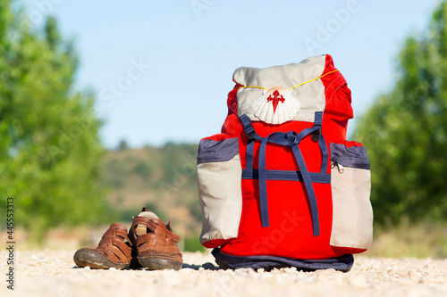 Way of St James , Camino de Santiago ,scallop shell on backpack on dirt road with old sandals to Compostela , Galicia, Spain