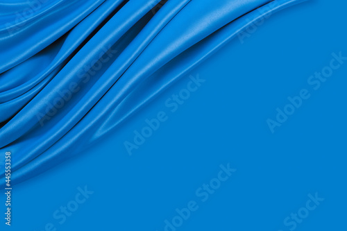 Beautiful elegant wavy blue satin silk luxury cloth fabric texture with monochrome background design. Copy space