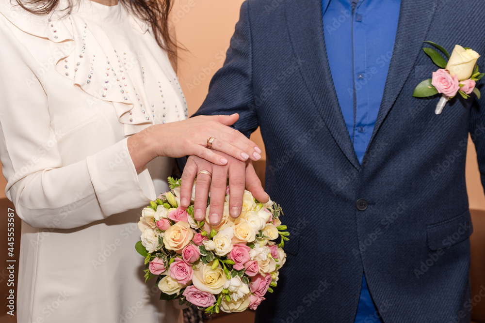 Bride and groom holding hands showing their rings, wedding couple holding bouquet Bride and groom holding hands showing their rings, wedding couple holding bouquet
