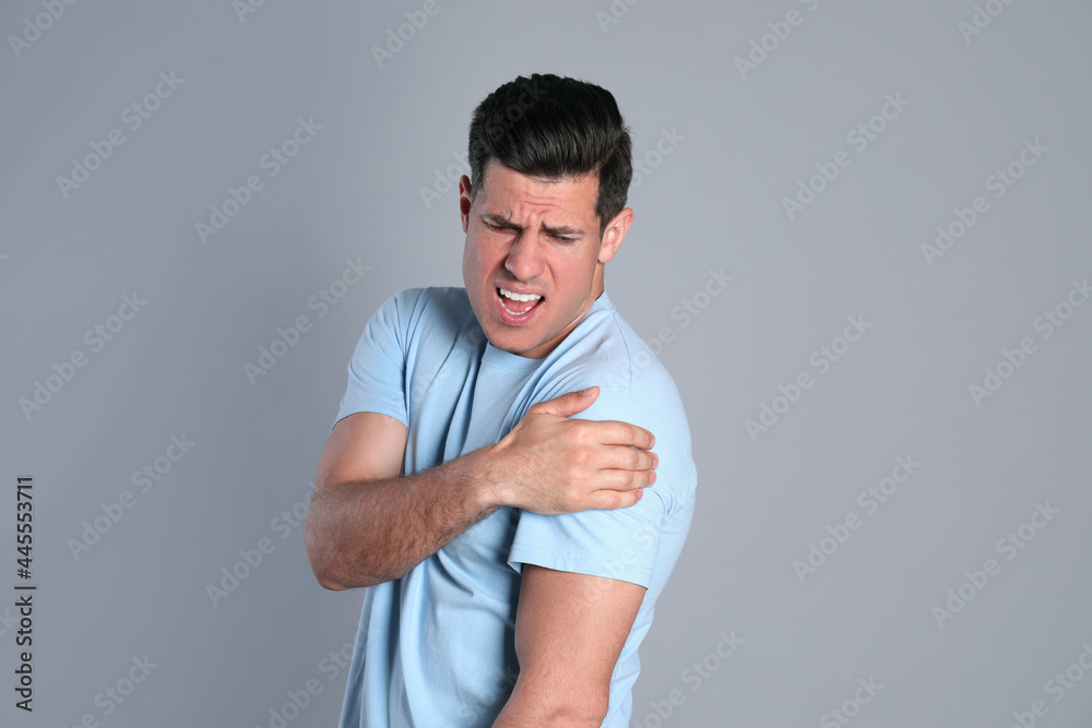 Man suffering from shoulder pain on grey background Man suffering from shoulder pain on grey background