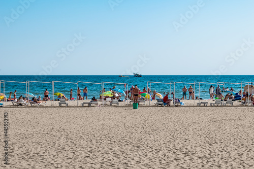 Zaliznyi Port, Ukraine - July 23, 2020: Beach coastline in the resort village of Zalizny Port. People are resting on white sand against a background of blue water © ioanna_alexa