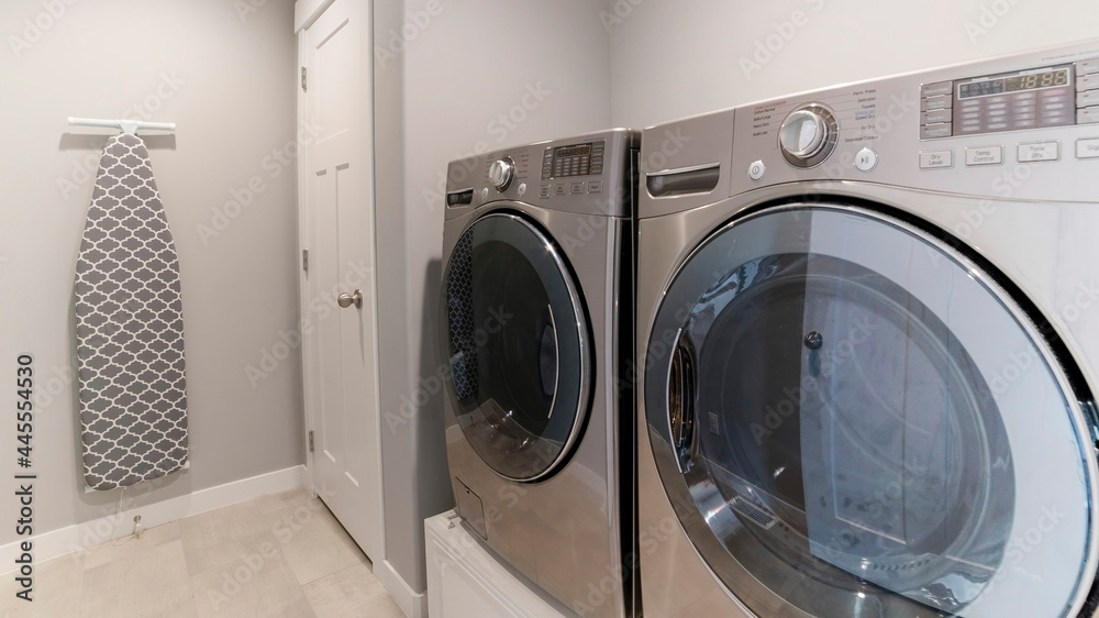 Pano Light gray laundry room with tiles, washer, dryer and storage room