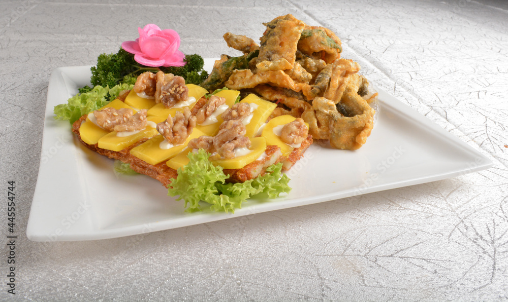 Deep fried egg skin crepe with mango fruit, walnut and salted egg yolk fish skin platter in white background appetiser halal menu Deep fried egg skin crepe with mango fruit, walnut and salted egg yolk fish skin platter in white background appetiser halal menu