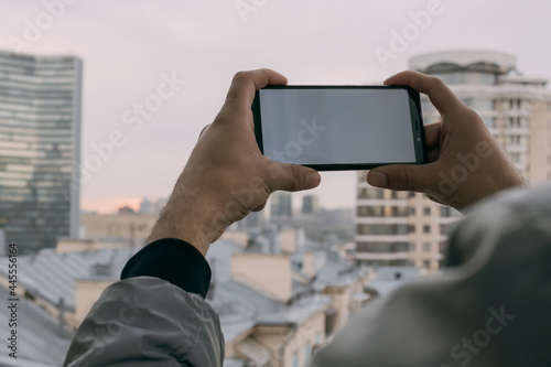 The telephone in men's hands against the background of the city landscape. Close-up.