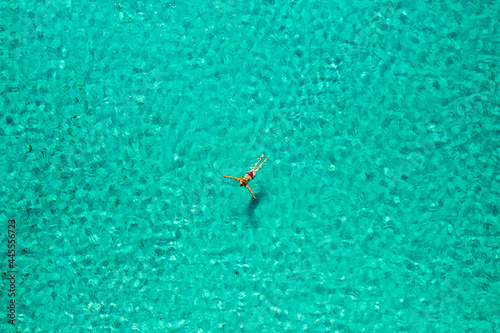 Aerial view of a girl floating in the turquoise sea of the Sakarun beach, Adriatic Sea, Croatia