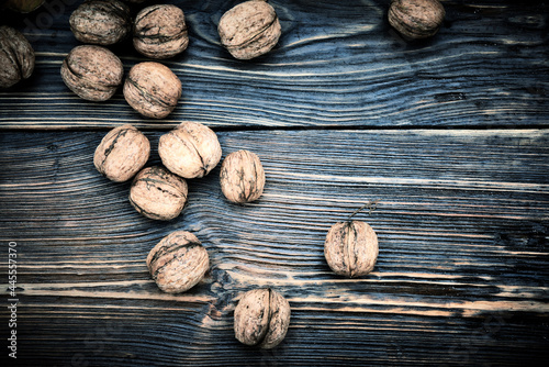 Whole walnuts lie on a rustic old wooden table. Harvest walnuts.