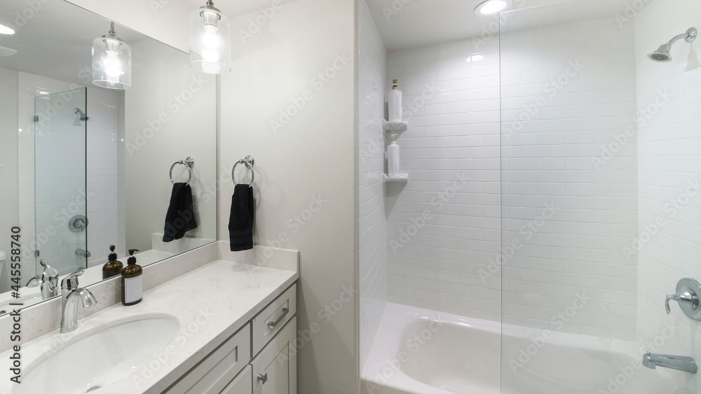 Pano Small modern plain white bathroom with an alcove bathtub with glass wall partition and white tiles Pano Small modern plain white bathroom with an alcove bathtub with glass wall partition and white tiles
