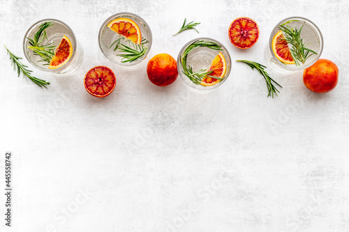 Red orange lemonade in glasses with ice and rosemary