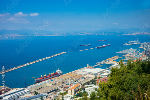 Cargo ships docked at the Port of Gibraltar, seen from a mountaintop on a clear summer day.