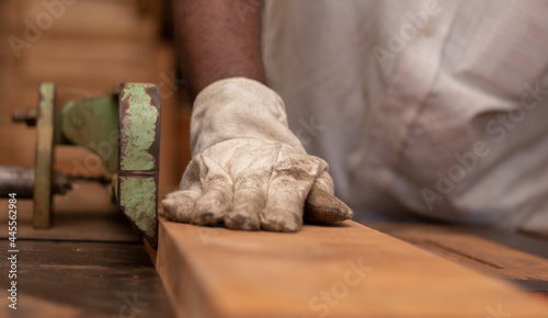 Closeup of a male wearing protective glove with dirt on a wooden photo