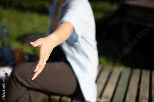 The girl holds out her hand. The girl in the park wants to take something in her hand.