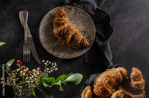 Vászonkép Brioches in low key with flowers on the dark grey table and napkin