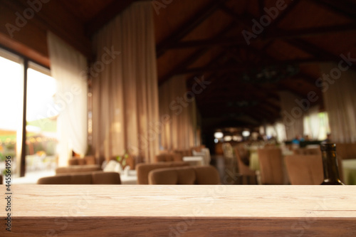 image of wooden table in front of abstract blurred background of lights of restaurant bar cafe