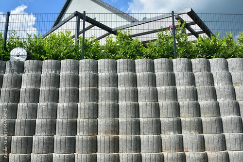 Stützmauer aus grauen runden Pflanzsteinen zur Hangsicherung und Abgrenzung eines Wohngrundstücks gegen die tiefer liegende Straße