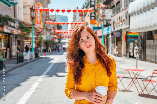 A young woman in a yellow shirt walks along a Chinese street in downtown San Francisco. A festive beautiful street with lanterns in the afternoon