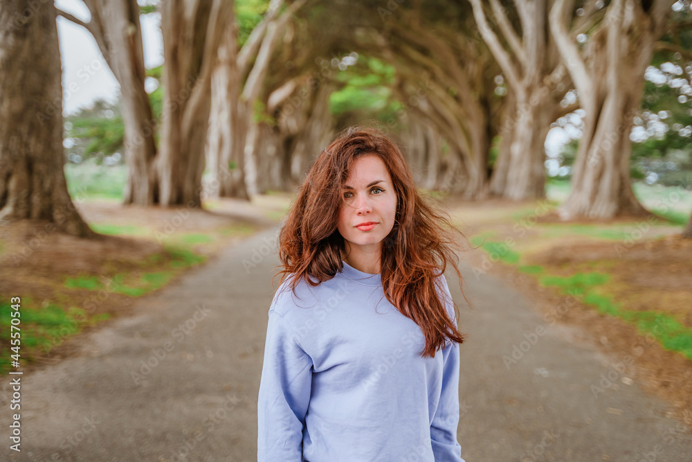 Inspiring portrait of a young woman with long hair in the atmospheric Cypress Tree Tunnel near San Francisco, USA Inspiring portrait of a young woman with long hair in the atmospheric Cypress Tree Tunnel near San Francisco, USA