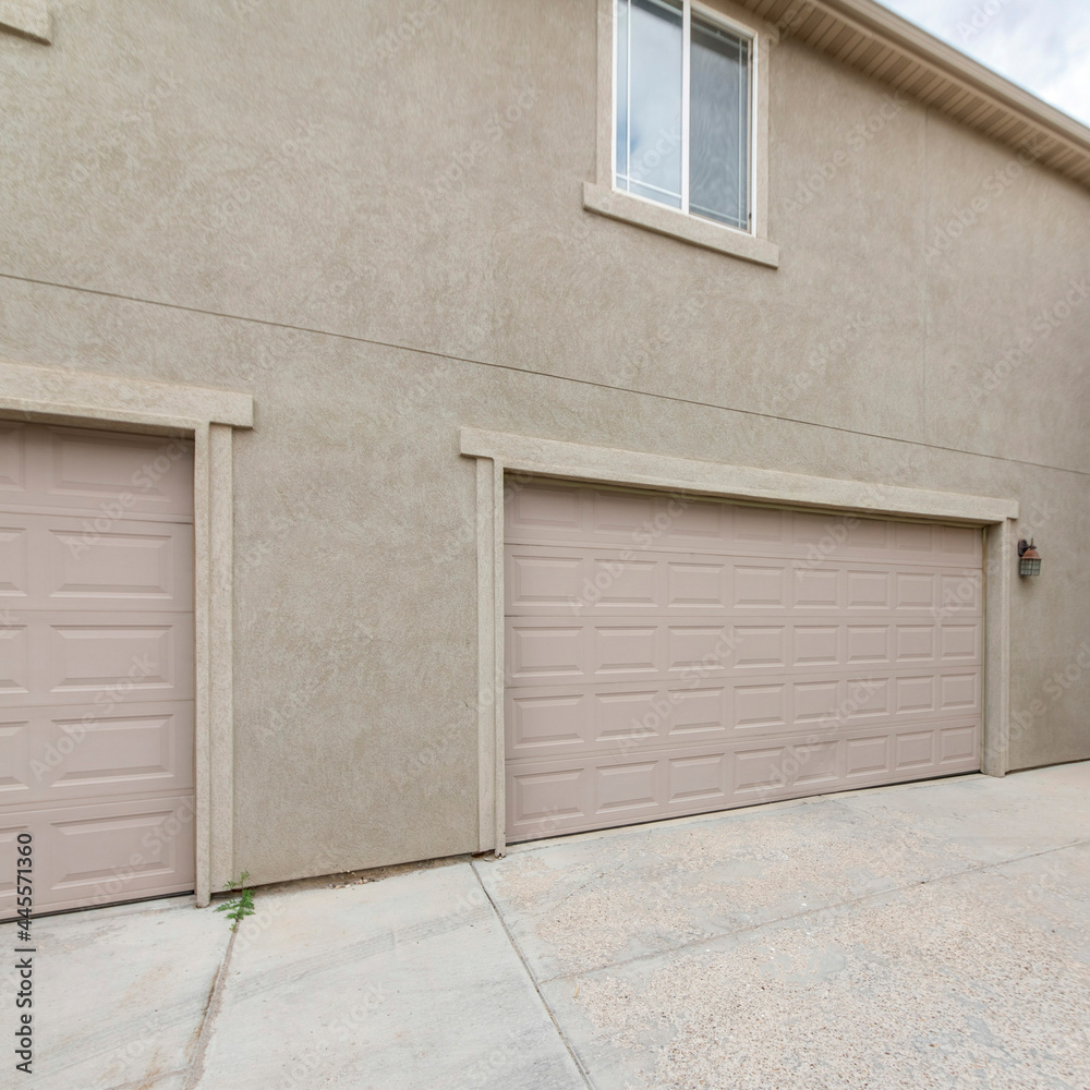Square frame Exterior of two buildings with concrete driveway, garage doors and windows Square frame Exterior of two buildings with concrete driveway, garage doors and windows