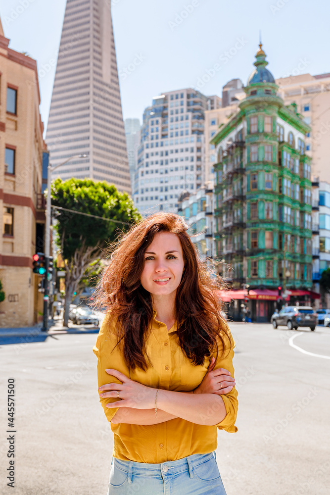 Beautiful young woman in a yellow shirt in a business center with a view of the Transamerica Tower in San Francisco