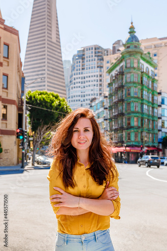 Beautiful young woman in a yellow shirt in a business center with a view of the Transamerica Tower in San Francisco